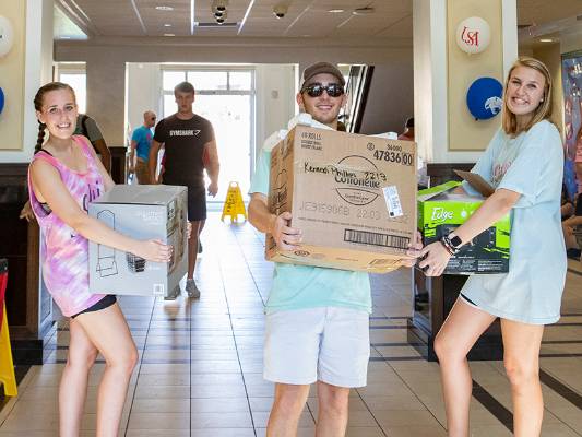 Students carrying boxes in hall